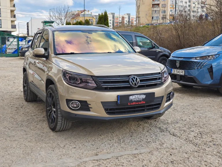 Volkswagen Tiguan — изглед отпред и отстрани с цветни отблясъци върху челното стъкло